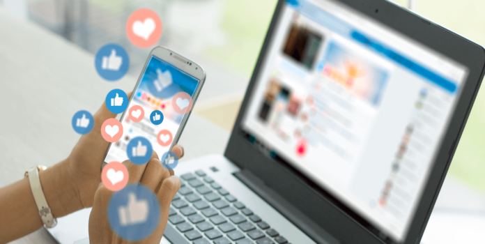 Social Media Strategies for Credit Unions person in front of a computer holding a phone with like icons floating above it