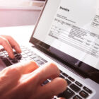Hands typing on a laptop