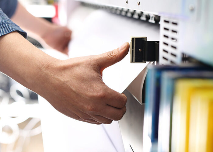 Person pulling paper out of commercial printer