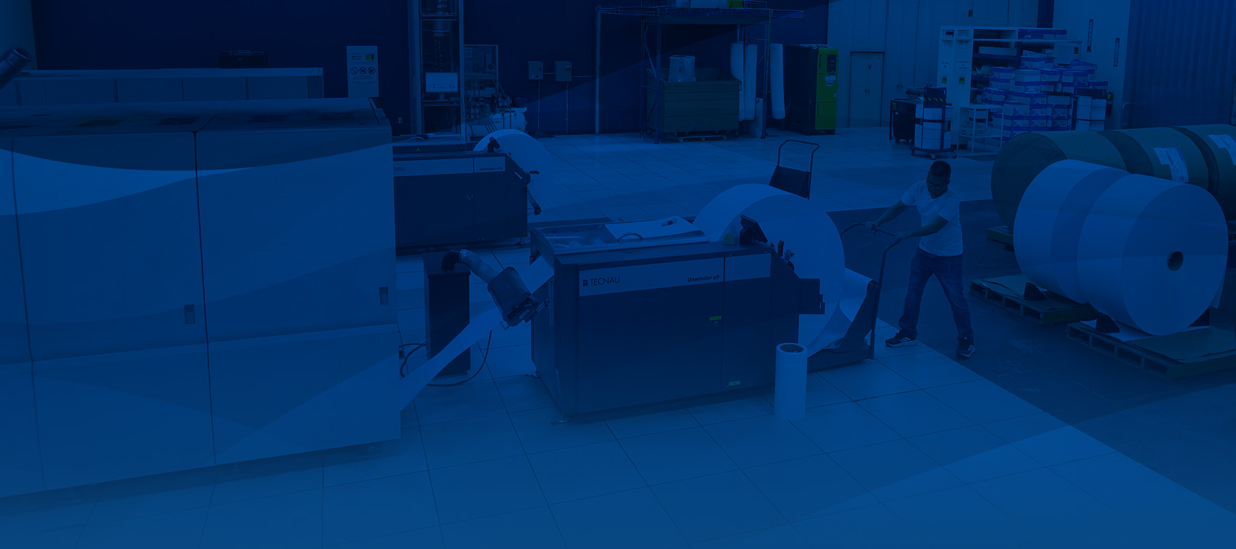 Worker in uniform lining up a stack of paper in a cutting machine