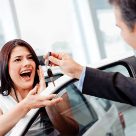Woman being handed car keys at a dealership