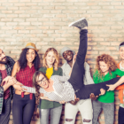 Image: a group of young adults holding up their friend.