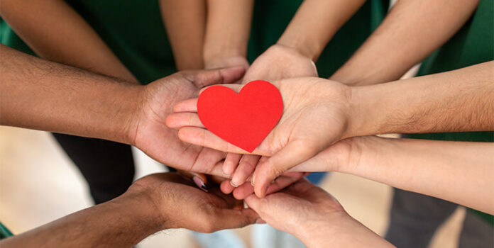 A collection of hands holding a paper cutout heart