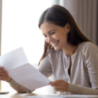 Woman holding letter and smiling.