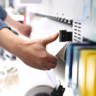 Person pulling paper out of commercial printer.