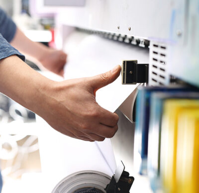 Person pulling paper out of commercial printer.